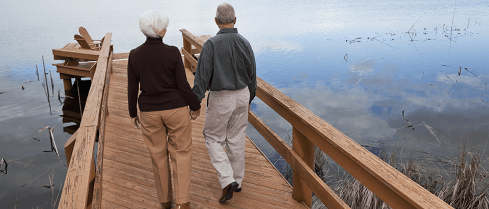 Older couple walking on dock holding hands